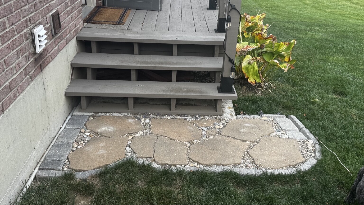 Stone landing with gravel joints at the bottom of a set of deck stairs