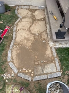 Landing stones and edging with tools and a bucket of rock nearby
