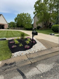 Finished mailbox garden bed with plants, dark mulch and white stone