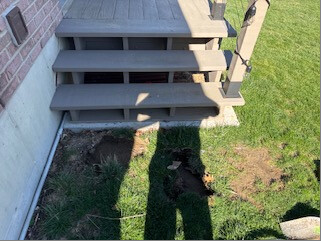 Ground beneath the deck stairs before the landing